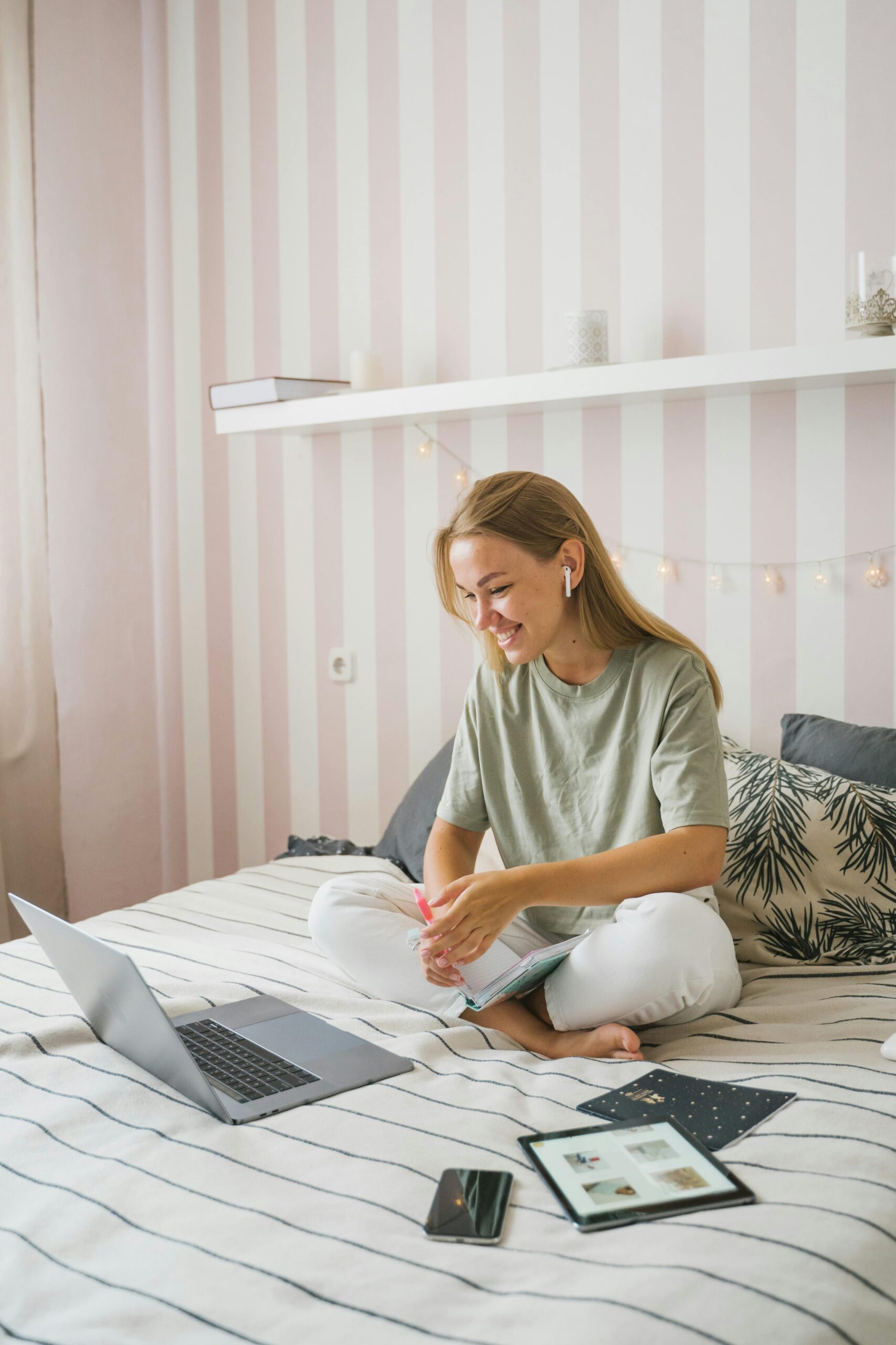 Woman enjoying an online education session while seated comfortably on her bed, using a laptop.